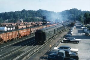 Western Maryland Railway | Elkins, West Virginia | Alco RS 3 diesel electric locomotive | Passenger train with coach and baggage cars | Yard view with coal hoppers | July 3, 1957 | George Leilich photograph